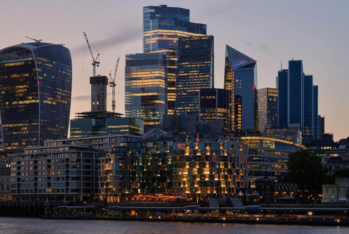 London skyline at dusk with iconic buildings and city lights near riverside apartments