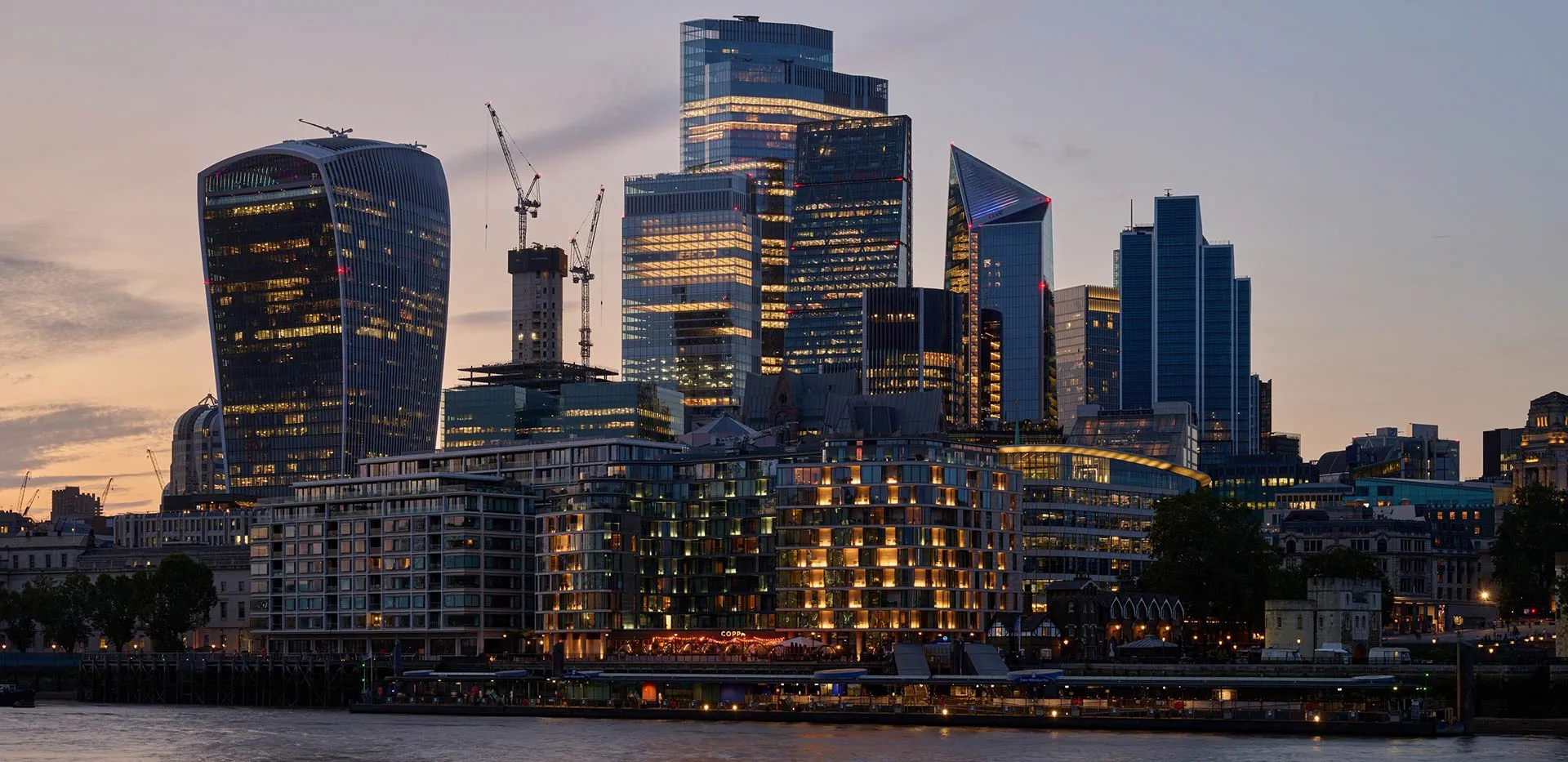 London skyline at dusk with iconic buildings and city lights near riverside apartments